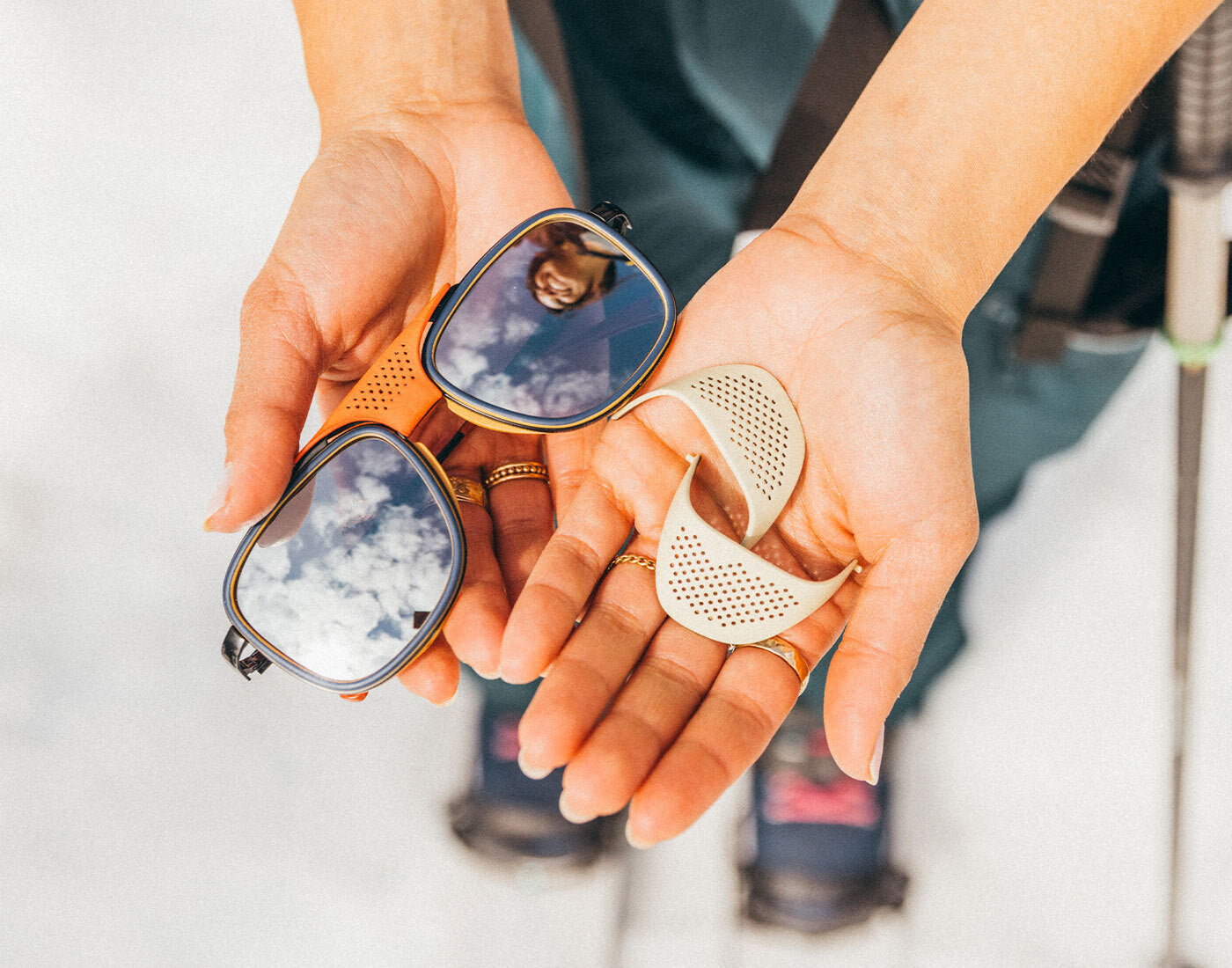 Person holding two pairs of sunglasses with reflective lenses.