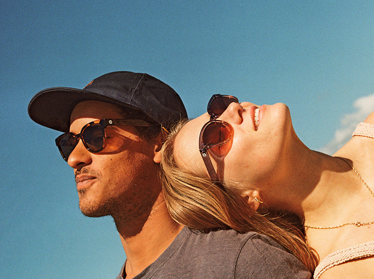 Two people wearing Sunski sunglasses against a clear blue sky