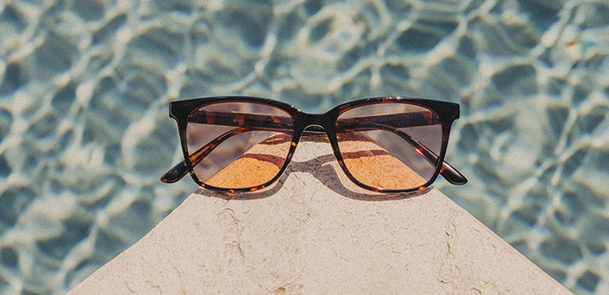 sunski tinted sunglasses on a corner by a pool 