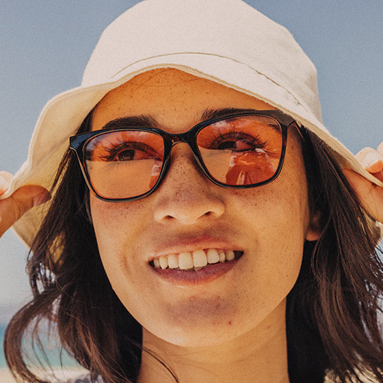 woman in hat wearing sunski tinted sunglasses