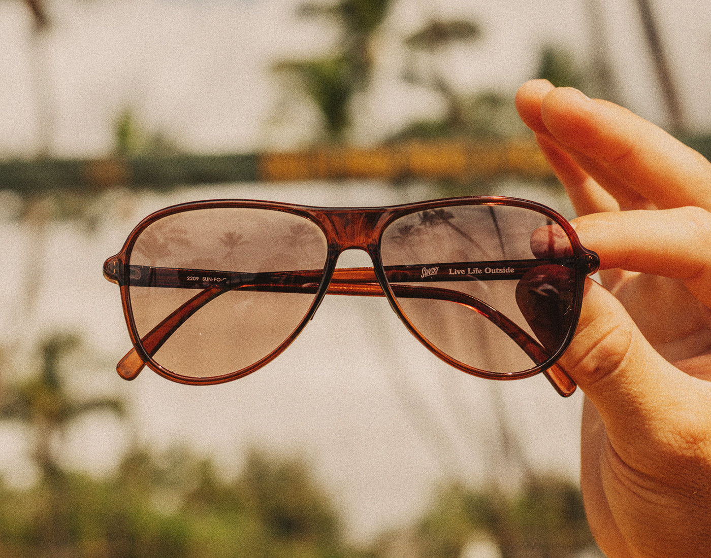 hand holding sunski foxtrot sunglasses in the air