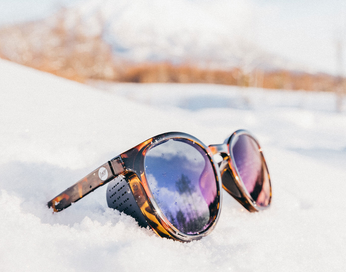 Sunglasses with reflective lenses on a snowy surface