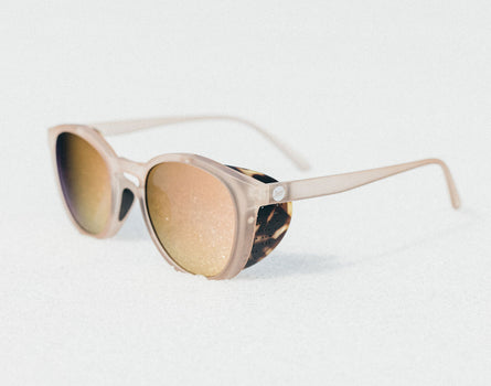 Sunglasses with beige frame and tortoiseshell accents on a light gray background