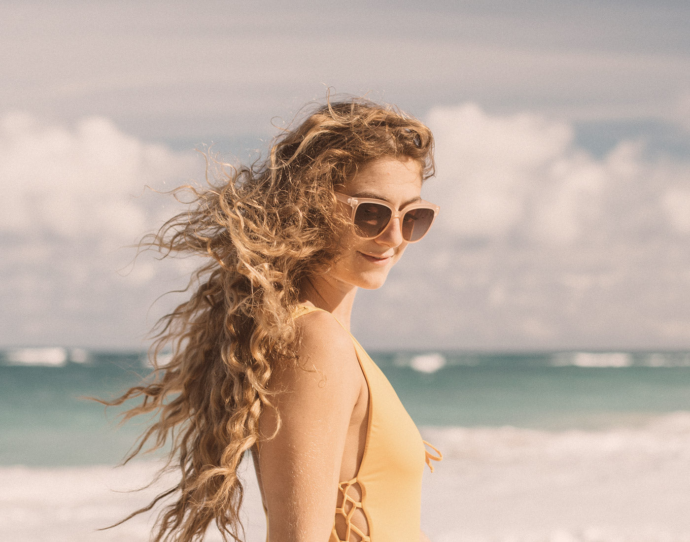 girl with wind blown hair wearing sunski camina sunglasses