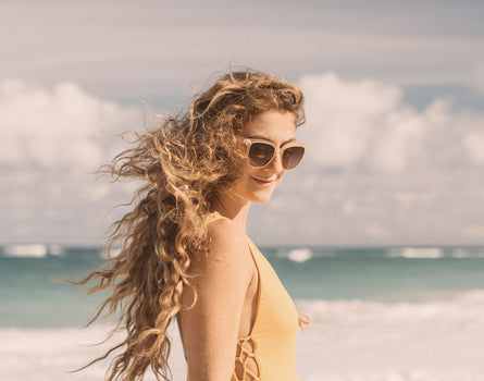 girl with wind blown hair wearing sunski camina sunglasses