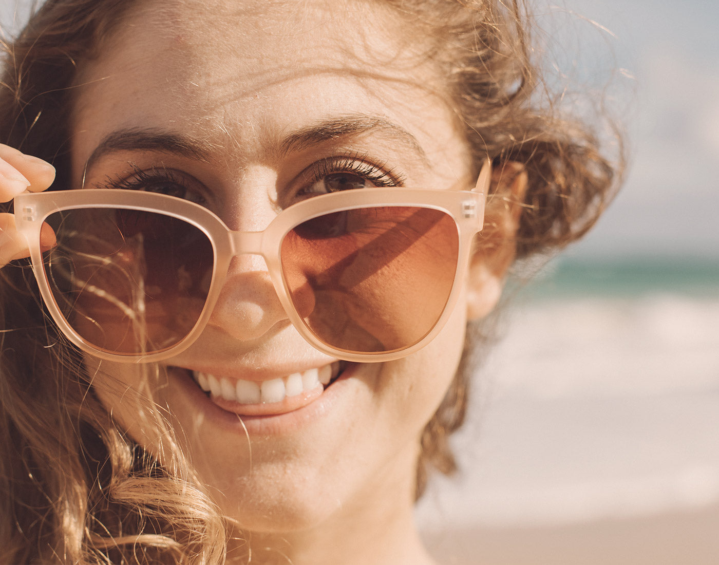 girl smiling looking over top of sunski camina sunglasses