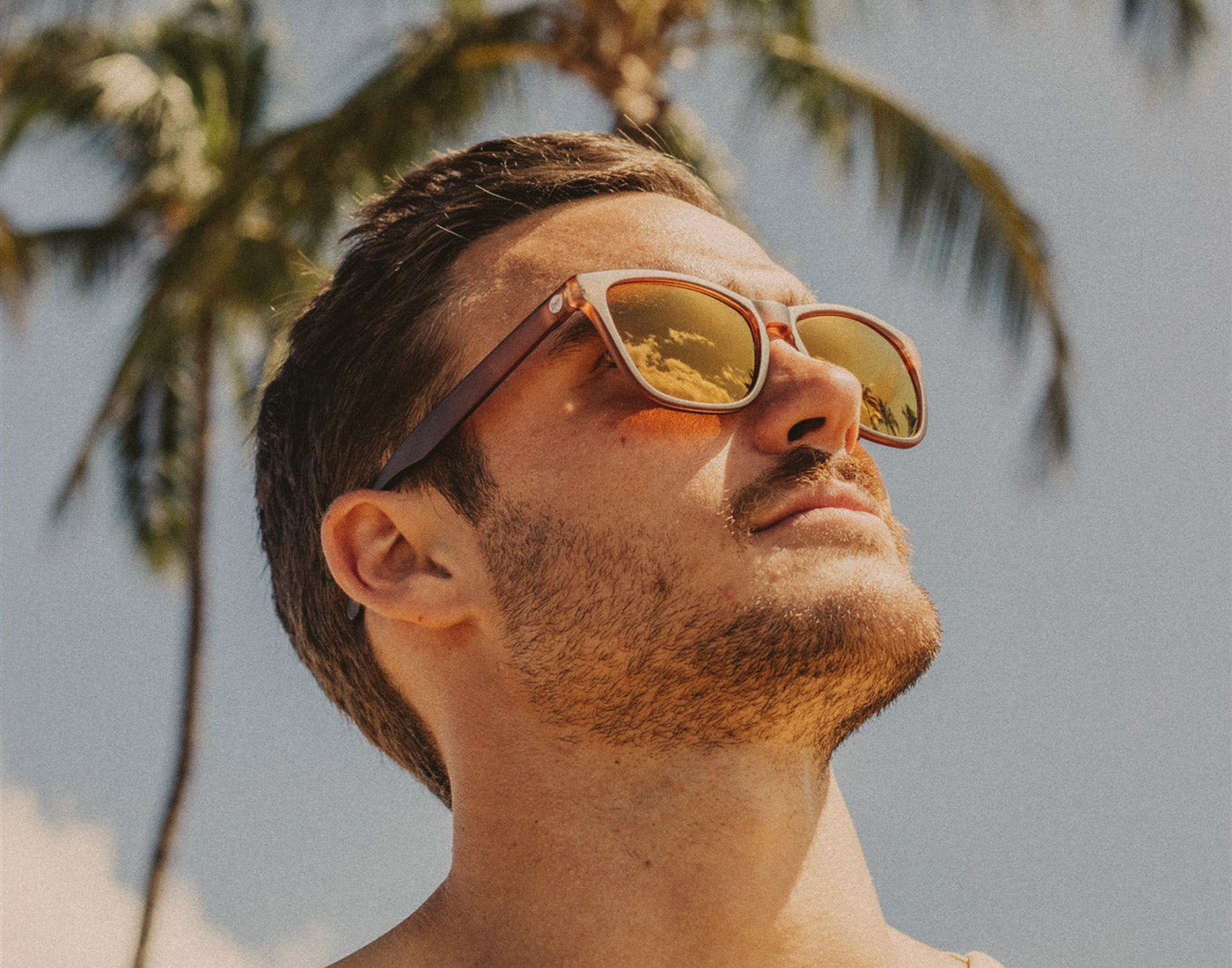 man looking up to sun wearing sunski headland sunglasses