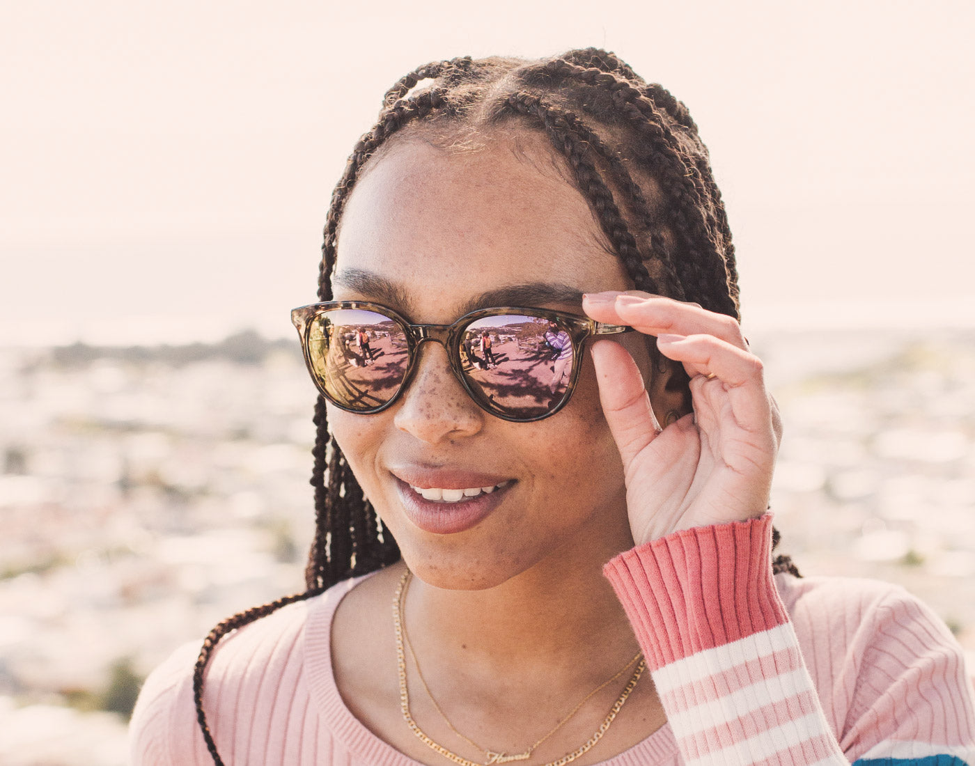 girl with hand holding sunski makani sunglasses to face
