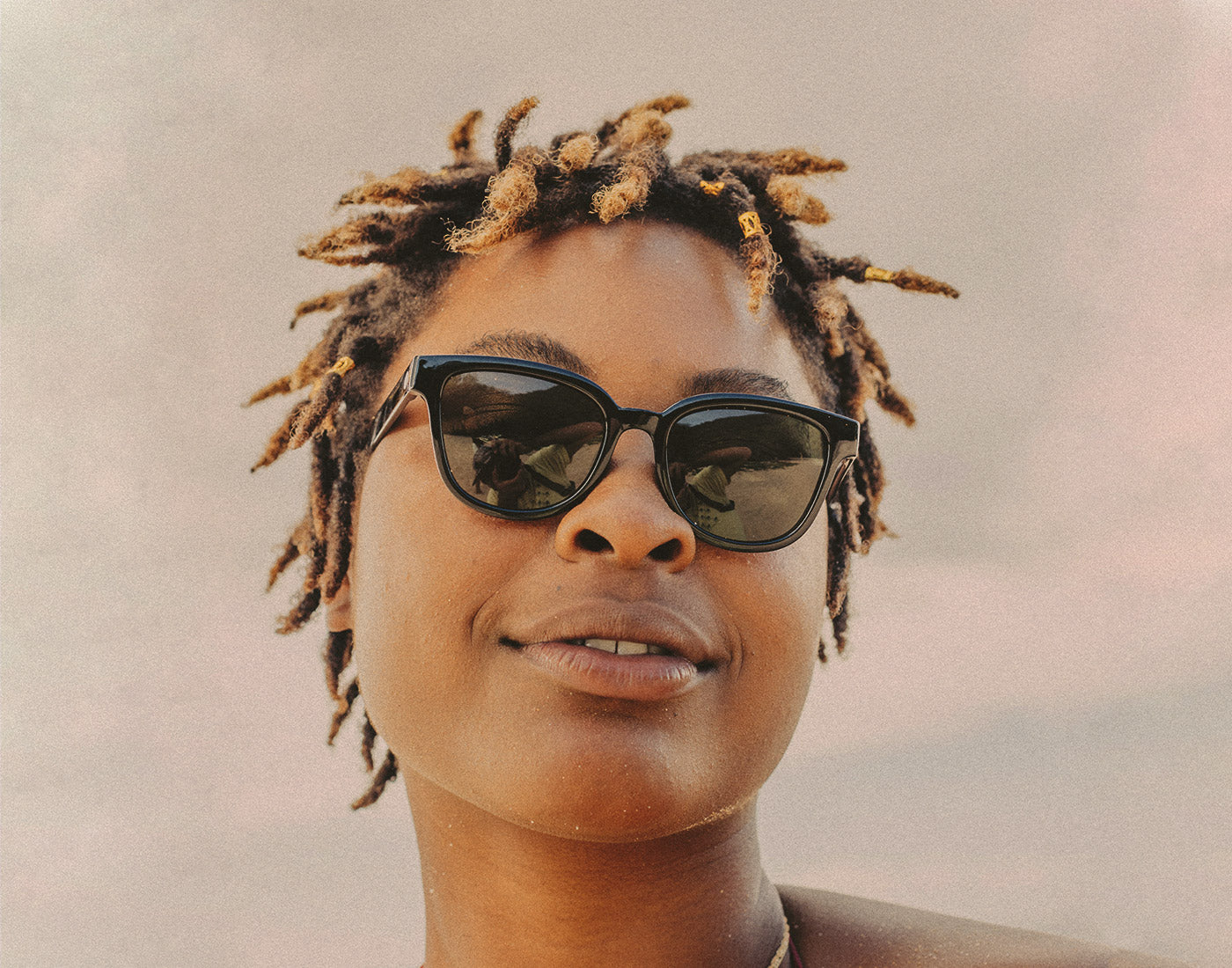 woman looking down at camera wearing sunski miho sunglasses