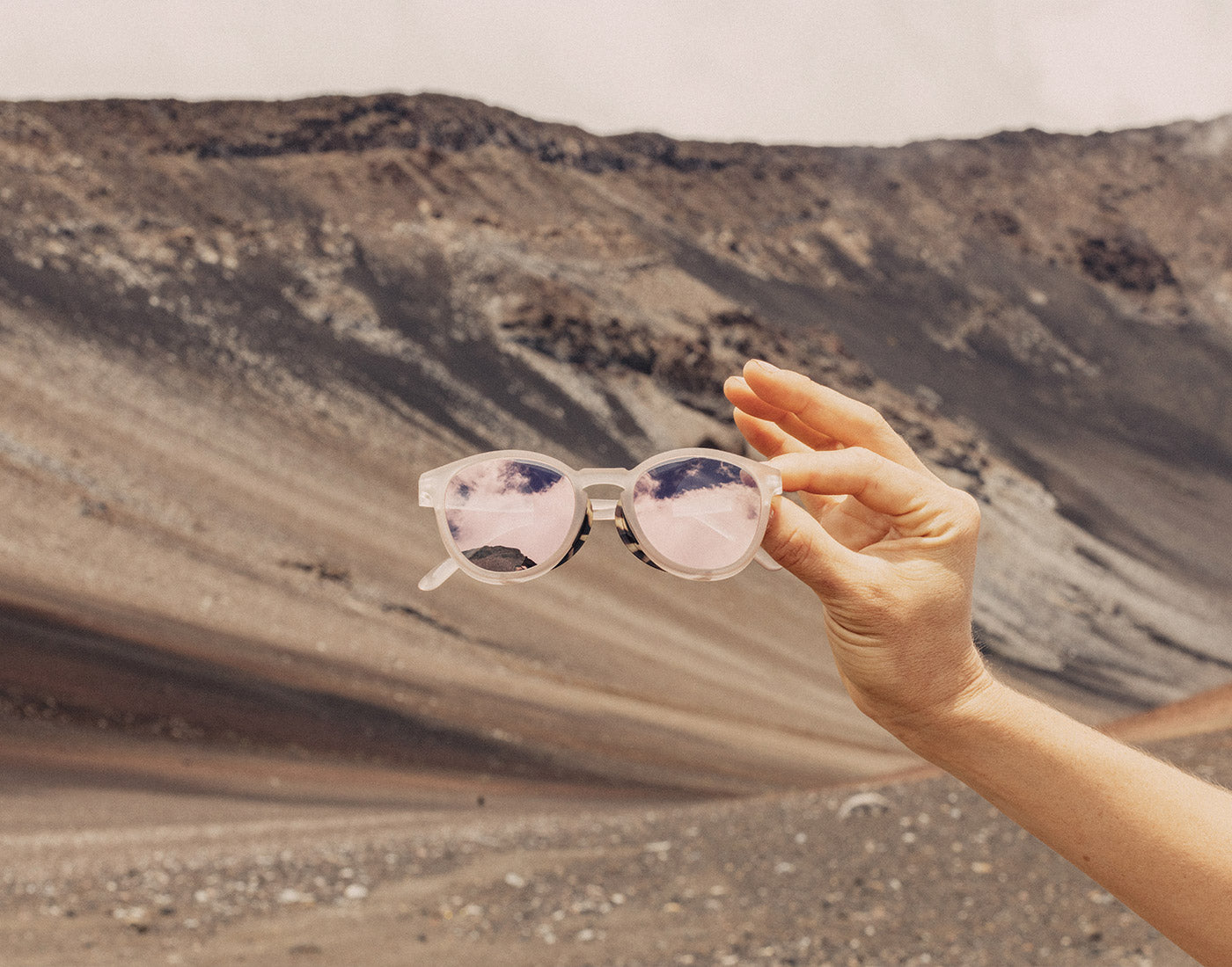 hand holding sunski tera sunglasses in front of mountain