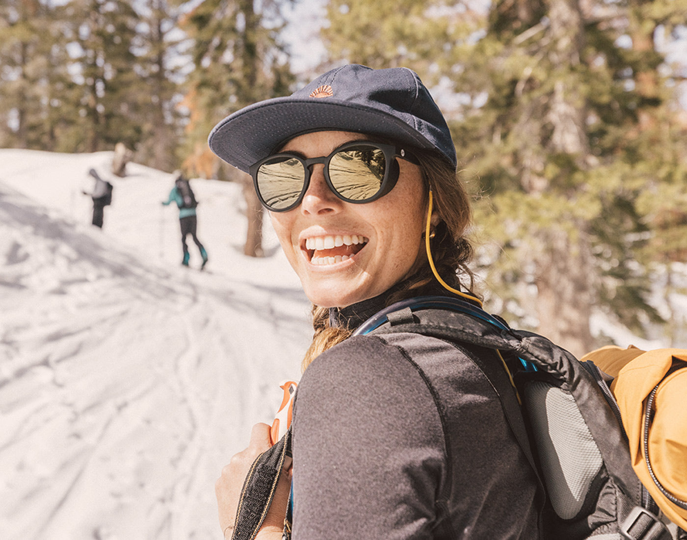 woman looking over her shoulder smiling wearing sunski sunglasses retainer