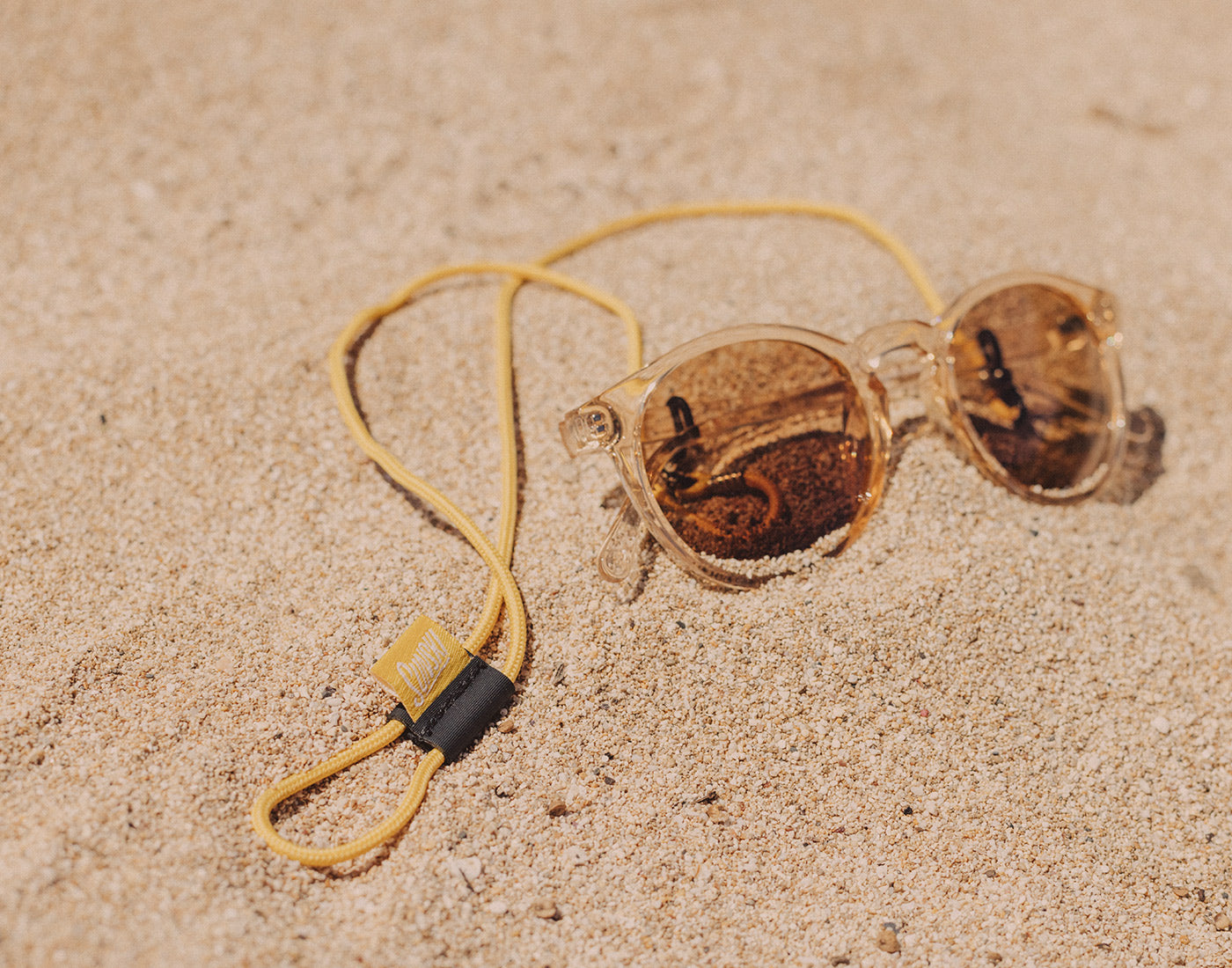 sunski sunglasses with a sunski sunglasses retainer in the sand