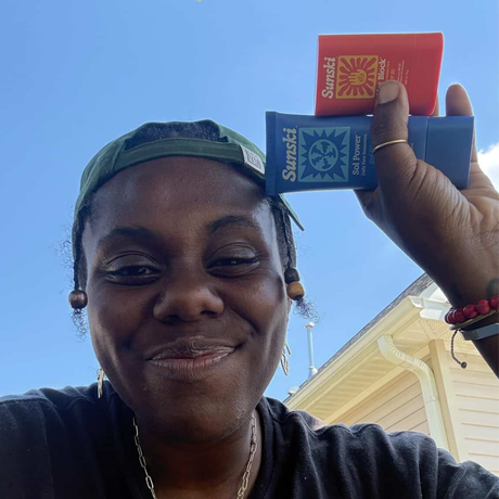 Person holding two Sunski SPFS (Hot Block and Sol Power) against a clear blue sky