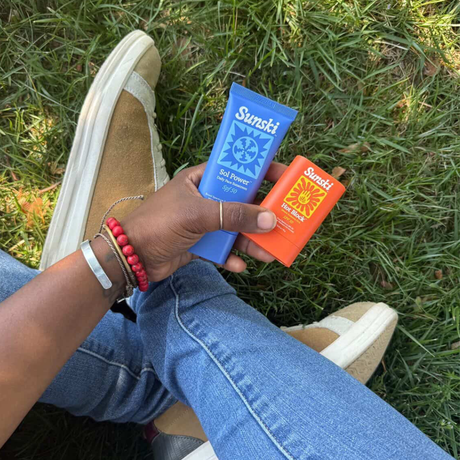 Person holding two Sunski products on grass