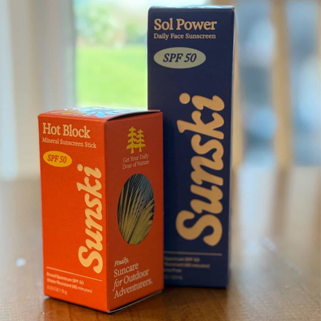 Two boxed Sunski sunscreen products on a surface with a blurred background