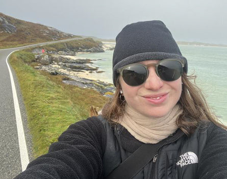 Person taking a selfie by a scenic road with ocean view