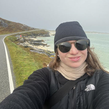 Person taking a selfie by a scenic road with ocean view