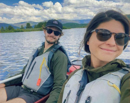 Two people in a kayak on a lake with mountains in the background