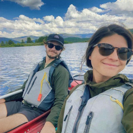 Two people in a kayak on a lake with mountains in the background
