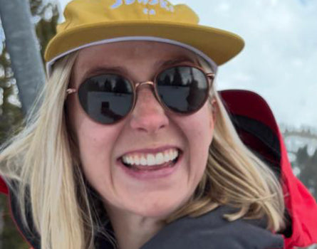 Person wearing a yellow cap and sunglasses with a snowy landscape in the background