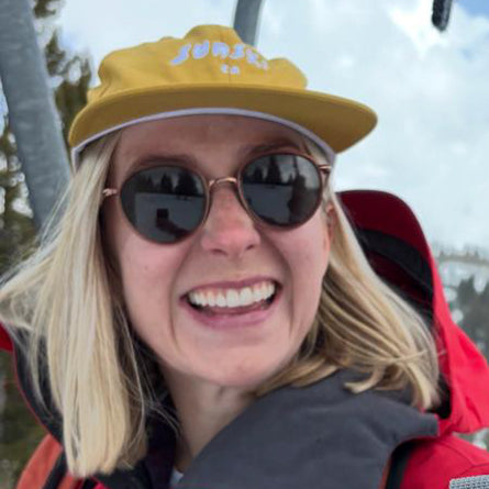 Person wearing a yellow cap and sunglasses with a snowy landscape in the background