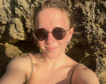 Woman wearing sunglasses in front of a rocky background