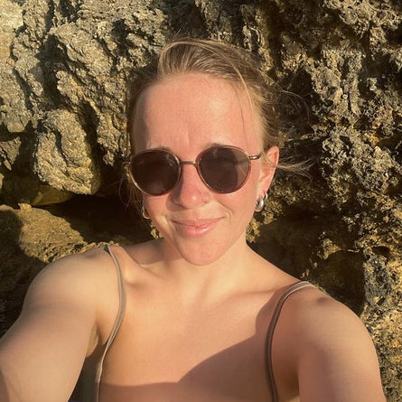 Woman wearing sunglasses in front of a rocky background