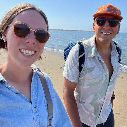 Two people on a beach with sunglasses and casual clothing