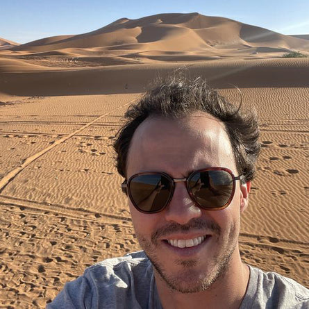 Man wearing sunglasses with desert landscape in the background