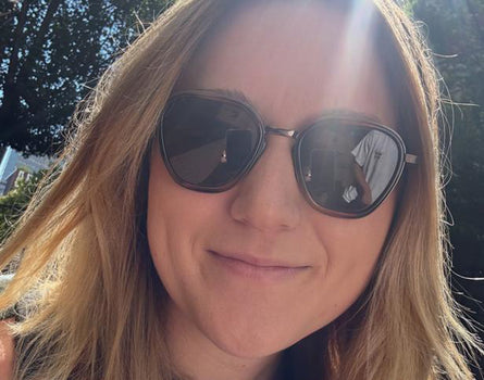 Person wearing sunglasses with a blurred outdoor background