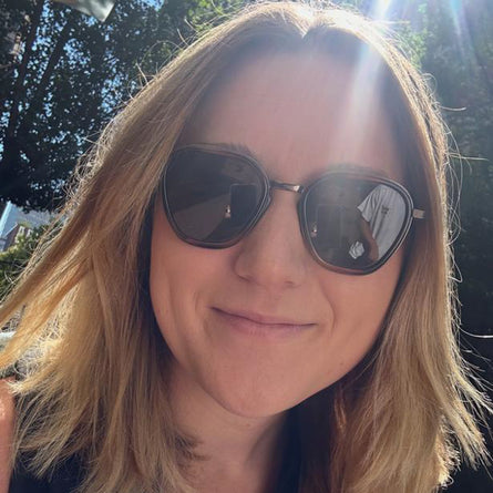 Person wearing sunglasses with a blurred outdoor background