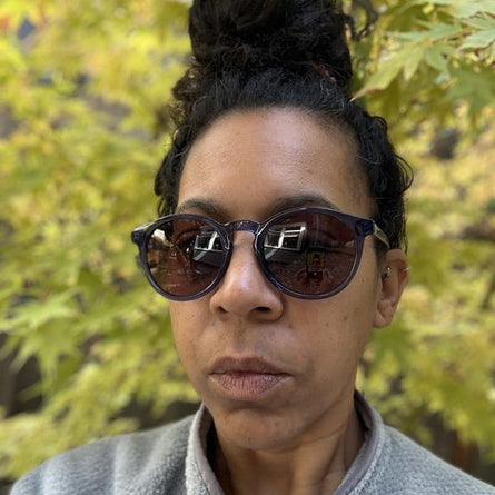 Person wearing sunglasses with a blurred natural background