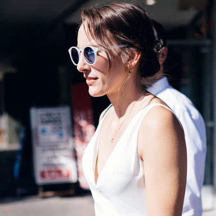 Woman wearing sunglasses and a white sleeveless top outdoors