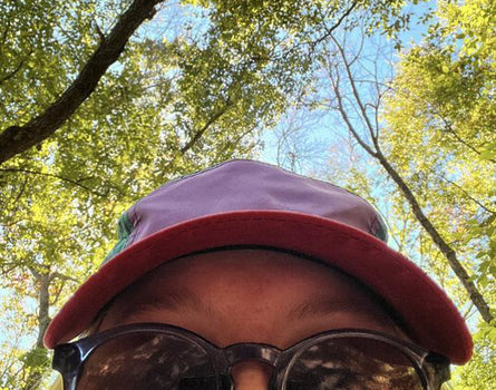 Person wearing a red cap and sunglasses with trees in the background