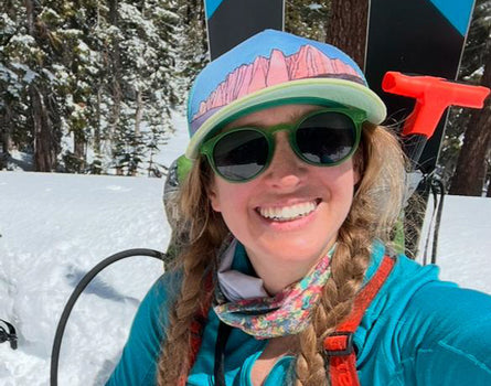 Person in winter gear with skis and poles in a snowy forest