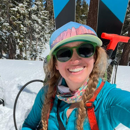 Person in winter gear with skis and poles in a snowy forest