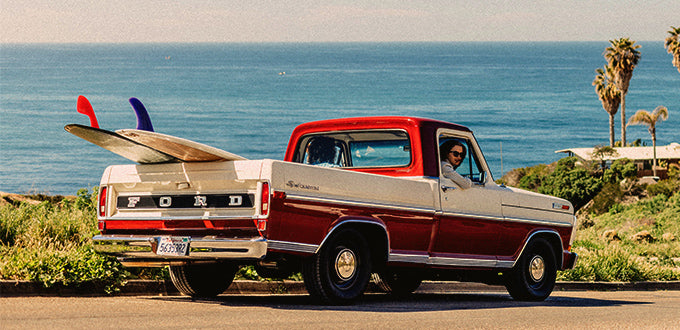 truck in front of the beach with surfboards in trunk 