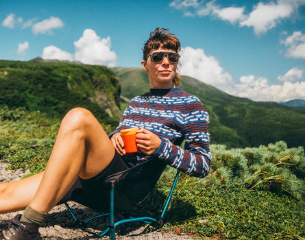 woman in sunski ferrata olive citrine amber drinking coffee in the mountains