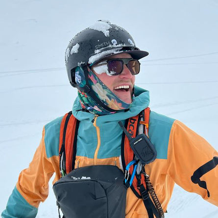 Person wearing a colorful jacket and helmet with a snowy background