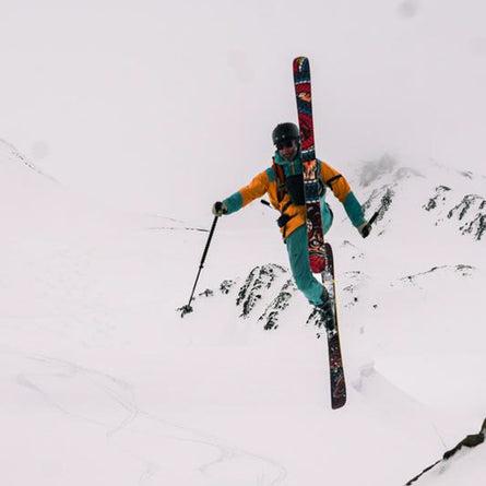 Person skiing with colorful skis in a snowy mountainous area