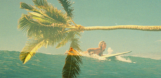 layered image of girl surfing and a palm tree
