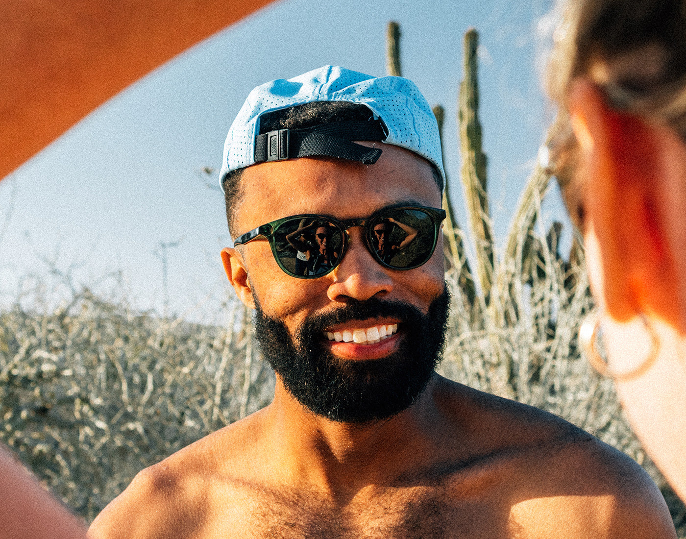 guy smiling wearing sunski chase the sun hat backwards