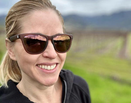 Woman wearing sunglasses with a blurred vineyard background
