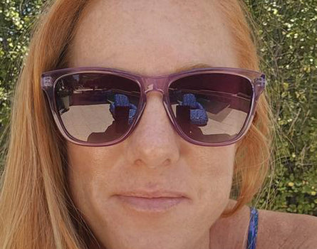 Person wearing purple sunglasses with a blurred natural background