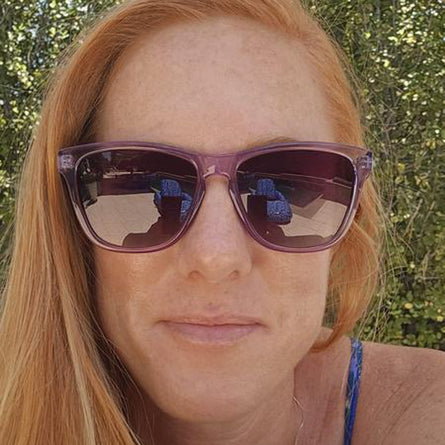 Person wearing purple sunglasses with a blurred natural background