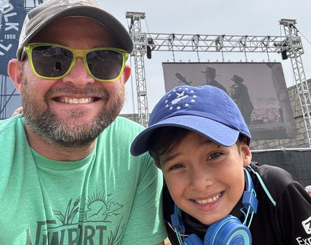 Man and child posing together with concert stage in the background
