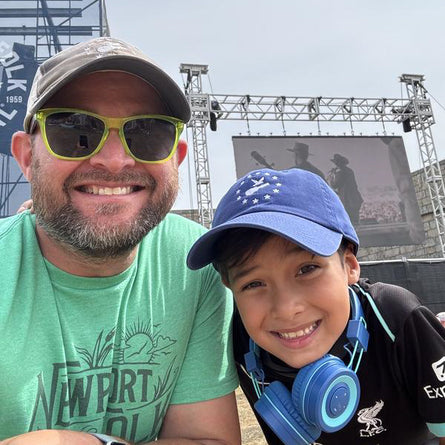 Man and child posing together with concert stage in the background