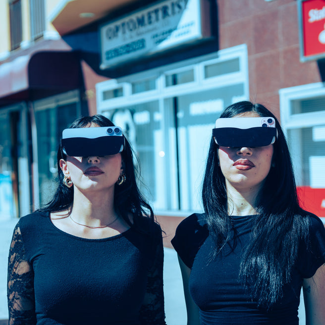Two women wearing futuristic visors on a city street.