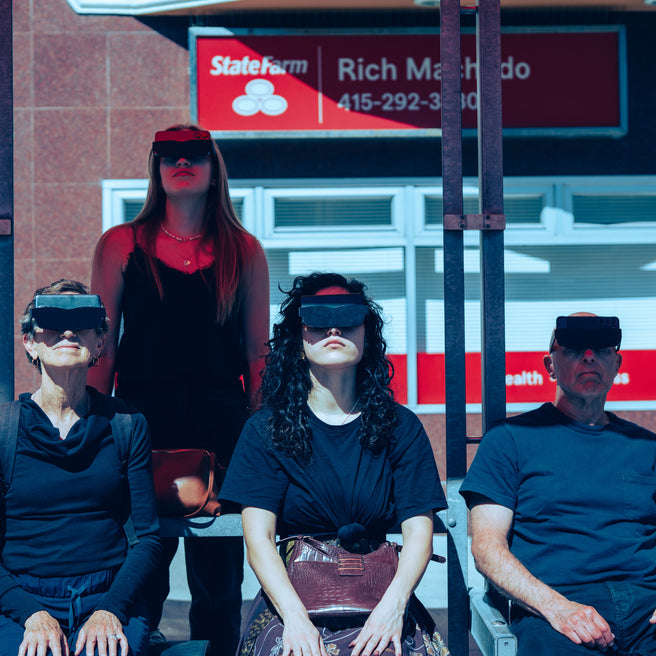 Four people wearing futuristic visors in front of a building.