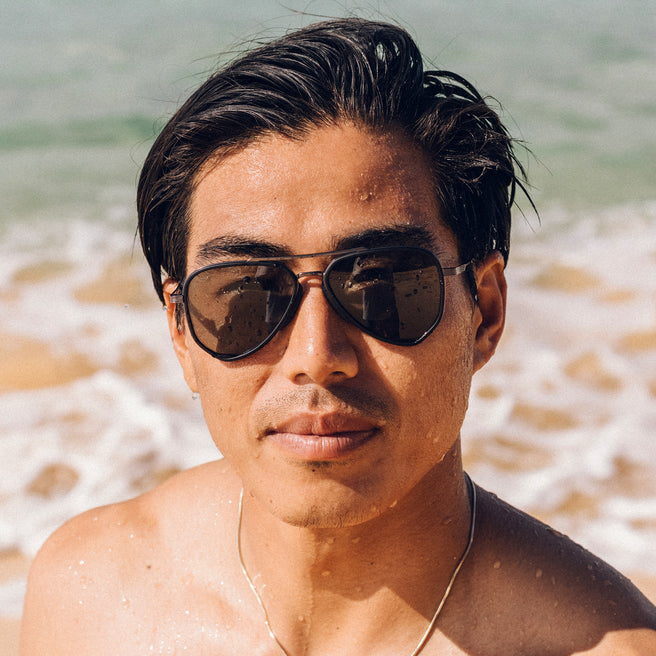 Man wearing sunglasses on a beach with ocean waves in the background
